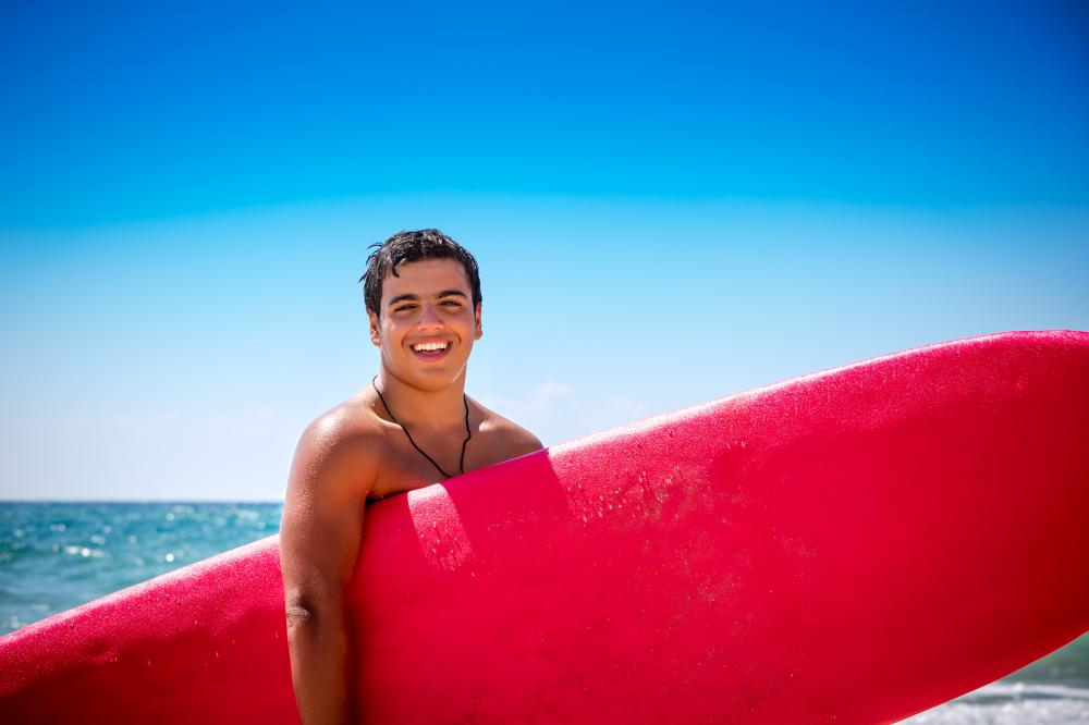 Joyful boy with surfboard representing the joy of safe water activities in New Jersey