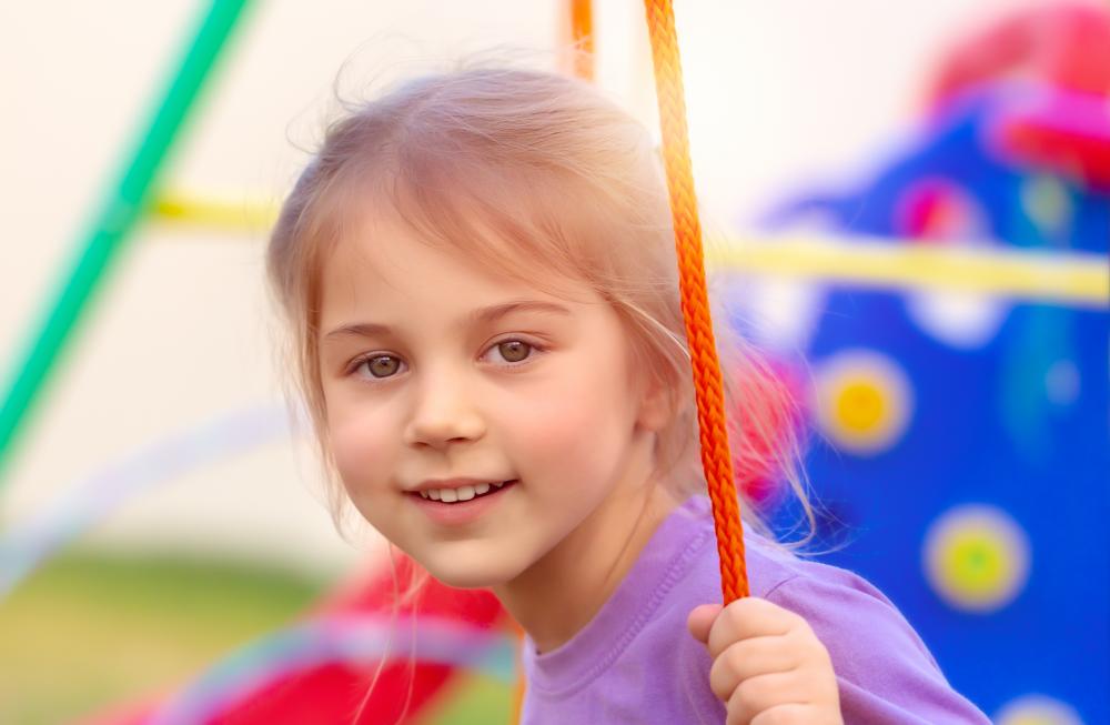 Joyful little girl swinging in a child day care center