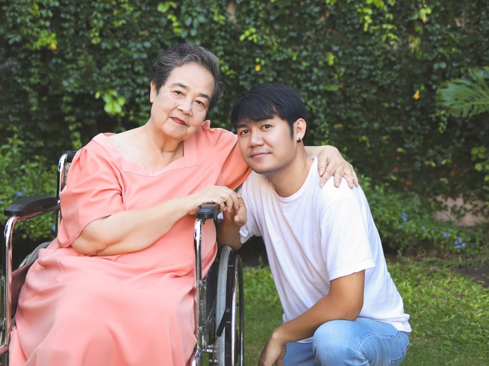 Asian senior woman on wheelchair with son, representing independence in living programs