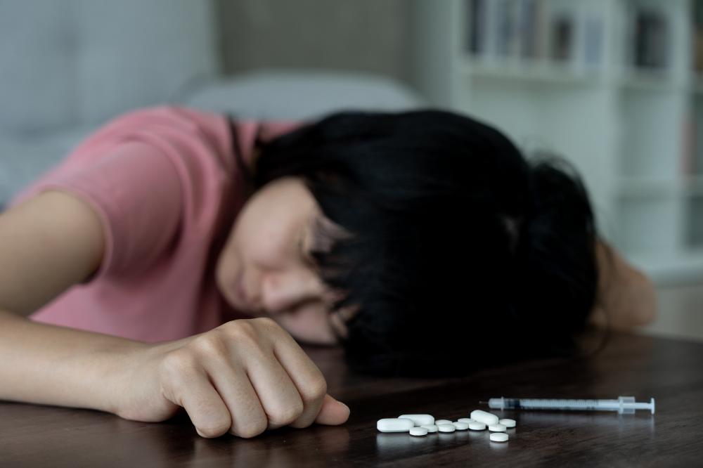 Asian woman confronting pill addiction as a symbol of drug rehab necessity