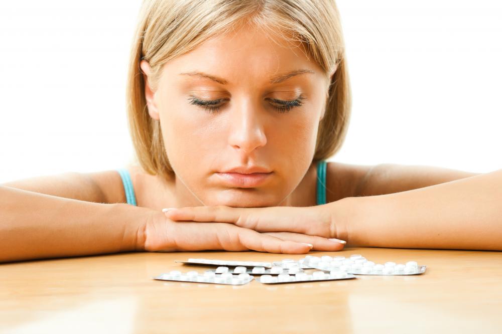 A reflective moment of a woman considering recovery as she looks at pills