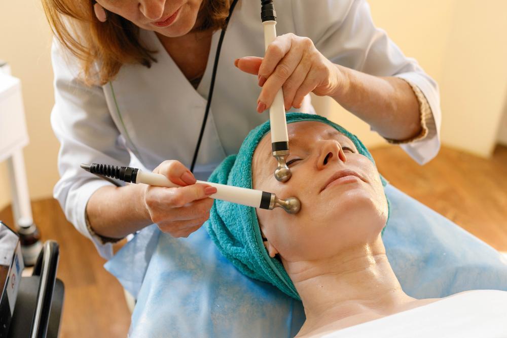 Professional cosmetologist providing microcurrent therapy