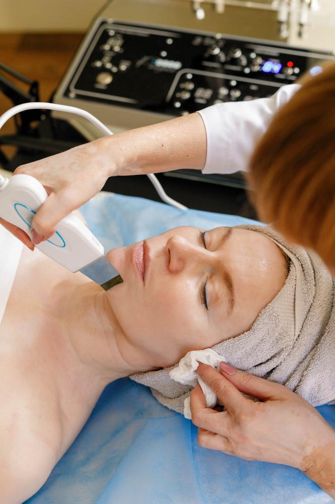 Expert cosmetologist performing ultrasonic face procedure