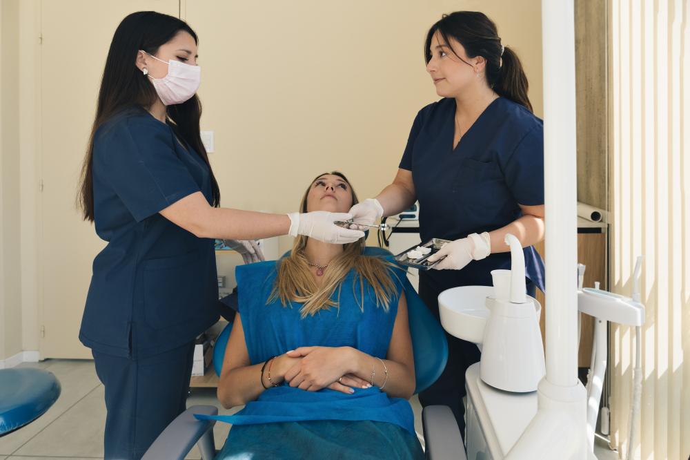 Female dentist and assistant performing a tooth extraction on patient