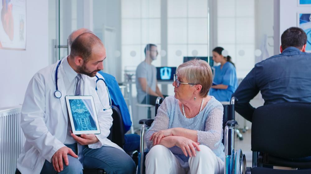 Doctor holding tablet with X-ray discussing sharp debridement techniques
