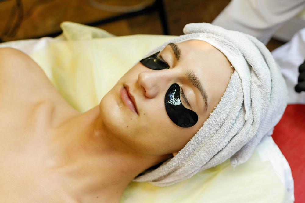 Cosmetologist applying facial mask during treatment session