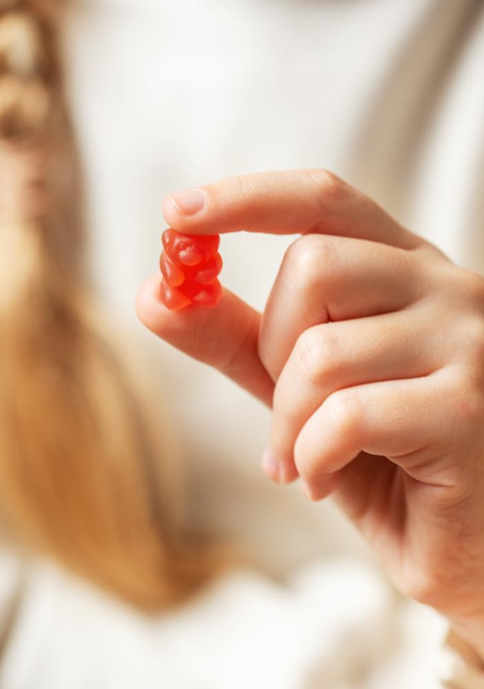 A girl enjoys CBD gummy bear vitamines