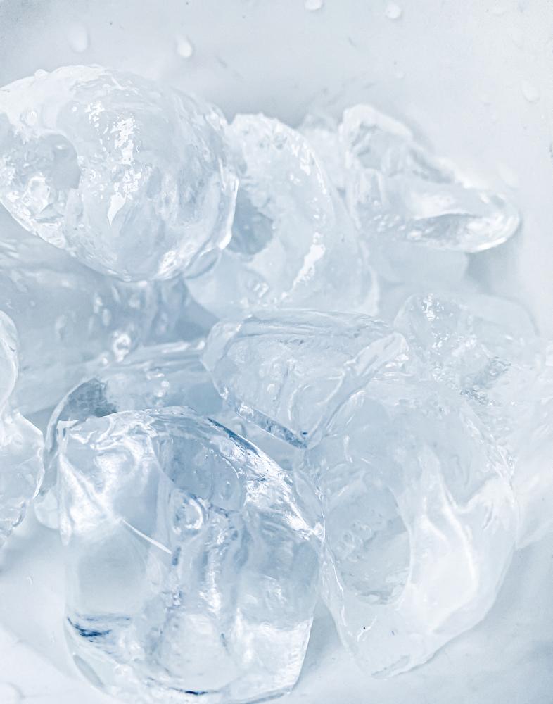 Close-up of clear ice cubes in a container, illustrating the quality and clarity of ice produced by industrial ice makers for food service and pharmaceutical applications.