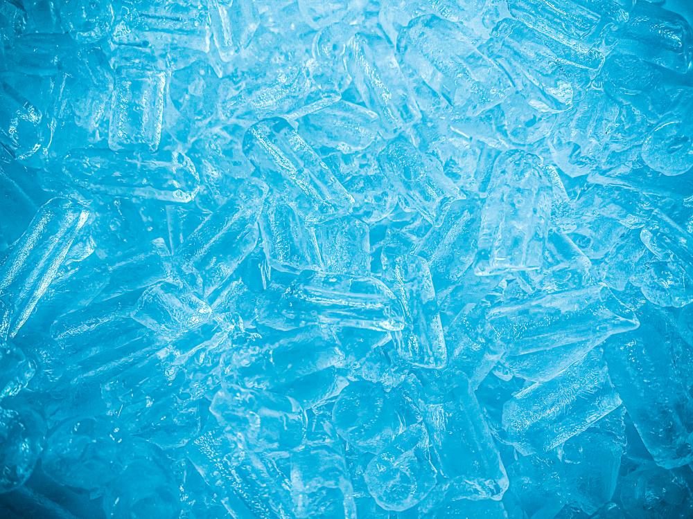 Ice cubes in a blue-toned background, emphasizing freshness and quality, relevant to industrial ice maker efficiency and performance in hot climates.