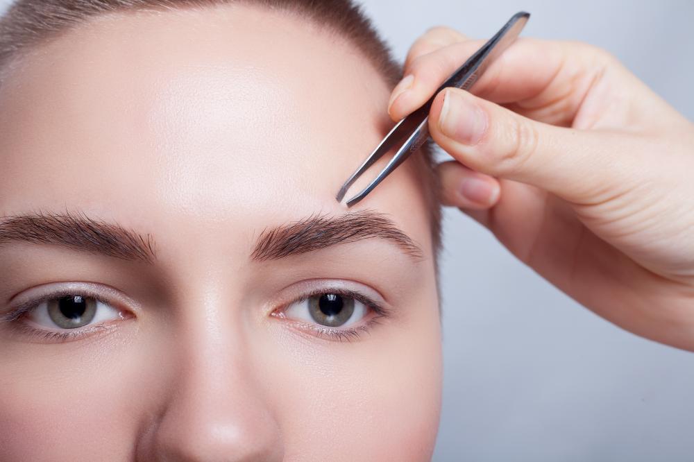 Focused Woman Plucking Eyebrows Representing Personal Grooming and Beauty Maintenance