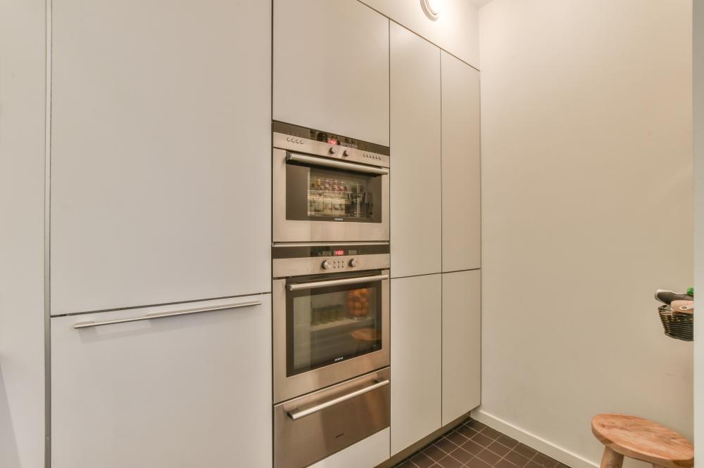 Modern kitchen featuring white cabinetry and Thermador oven stacked with a sleek design, emphasizing appliance repair and maintenance.