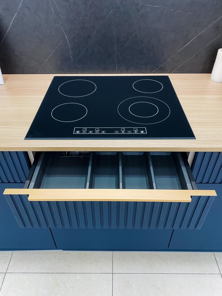 Modern Thermador Freedom Induction Cooktop on sleek wooden worktop with organized drawer below, emphasizing contemporary kitchen design and appliance functionality.