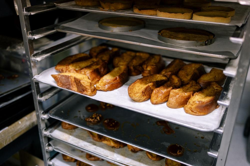 Tray of freshly baked French toast slices on parchment paper in a commercial kitchen, showcasing golden-brown pastries, relevant to Thermador double wall oven features and cooking expertise.