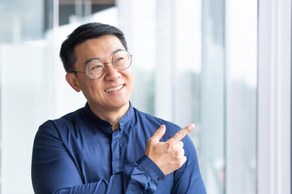 Businessman in glasses smiling and pointing, representing expertise in Seattle SEO strategies and local market insights.