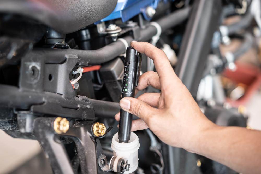 Technician checks brake fluid level during motorcycle maintenance